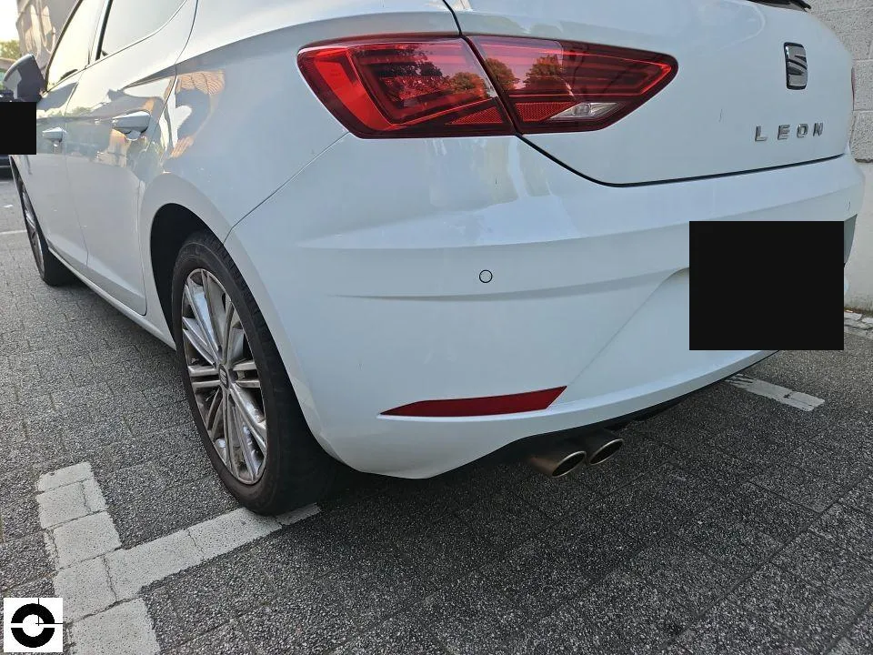 Rear of a white Seat Leon with a replaced bumper in a car park, licence plate blurred