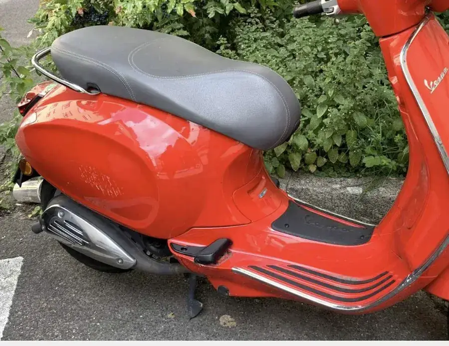 Оранжевый мотороллер (Vespa) с повреждениями от падения