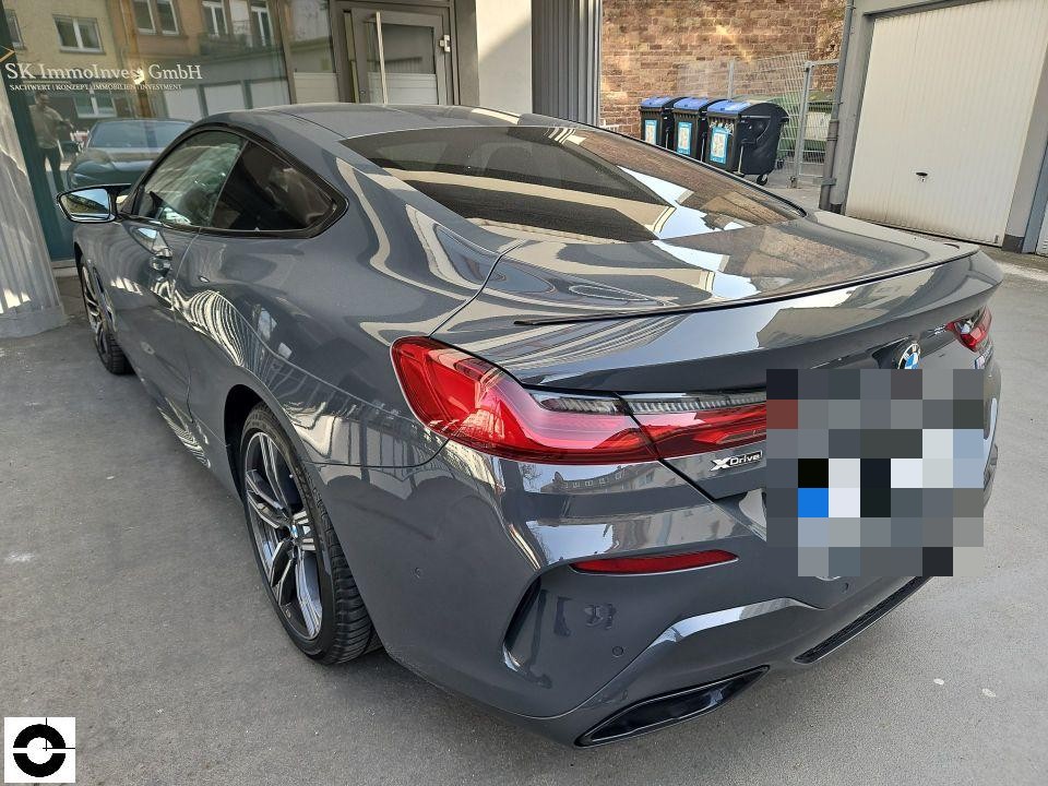 Heckansicht schräg links, dunkelgraues Coupé, keine sichtbaren Schäden