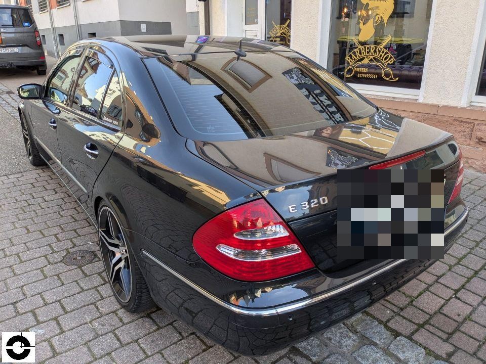 Heckansicht schräg links, schwarze Limousine E320, Kennzeichen pixeliert, keine sichtbaren Schäden