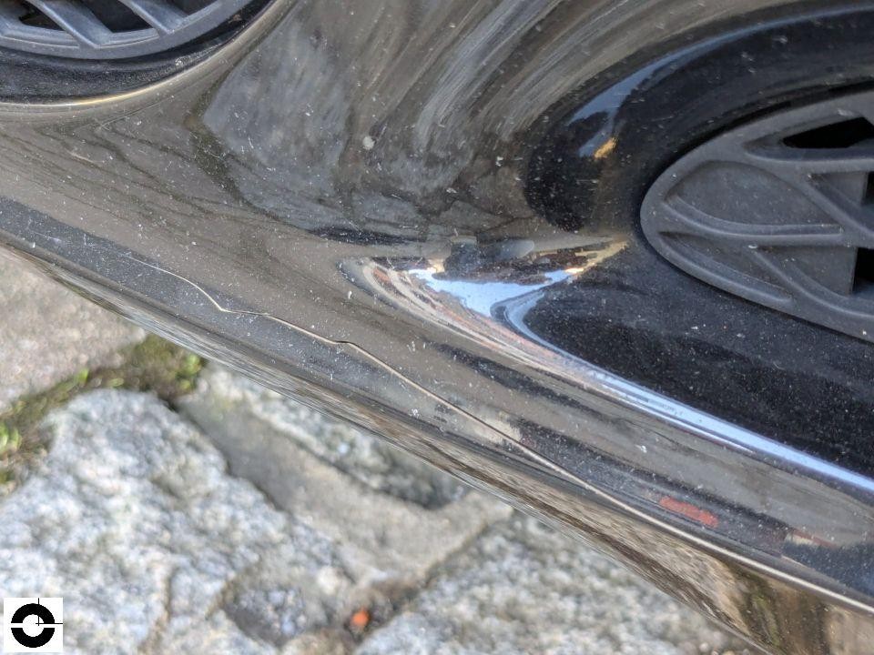 Nahaufnahme Radlauf hinten links mit Kratzern und Lachabplatzungen am schwarzen Kotflügel