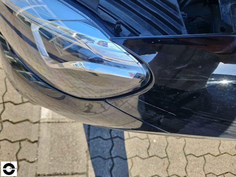 Nahaufnahme linker Frontscheinwerfer mit Kratzern an der Stoßstange