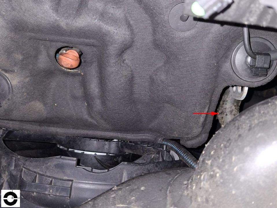 Motorraum-Detailaufnahme, Unterbodenverkleidung mit rotem Pfeil auf Schadenstelle