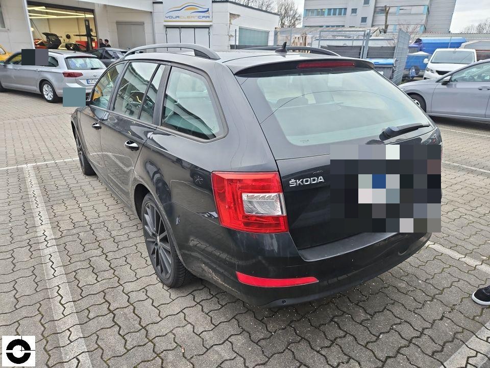 Heckansicht schräg links, schwarzer Kombi auf Parkplatz, keine sichtbaren Schäden