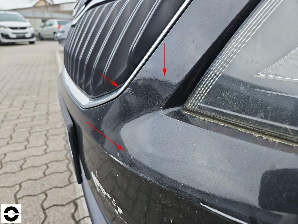 Nahaufnahme Frontbereich links, Kratzer an Stoßfänger und Kühlergrill mit Markierungspfeilen