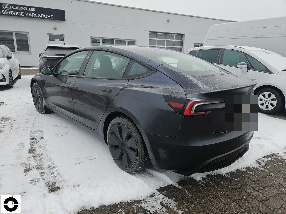 Heckansicht schräg links, dunkelgraues Fahrzeug auf verschneitem Parkplatz, keine sichtbaren Schäden