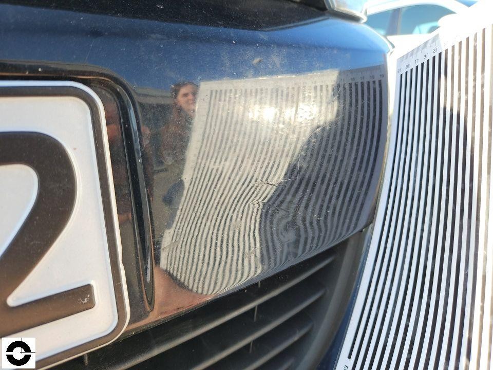 Nahaufnahme rechter Frontscheinwerfer mit Lineal zur Schadensdokumentation, Kratzer sichtbar