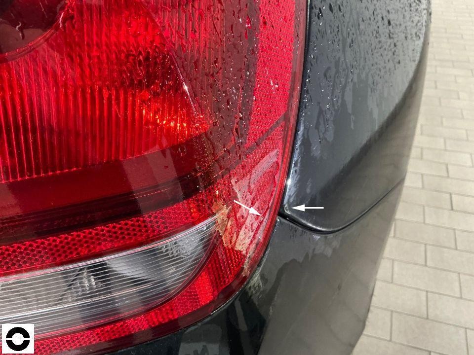 Detailaufnahme Rückleuchte links mit Pfeilmarkierung auf Kratzer am Übergang zur Karosserie
