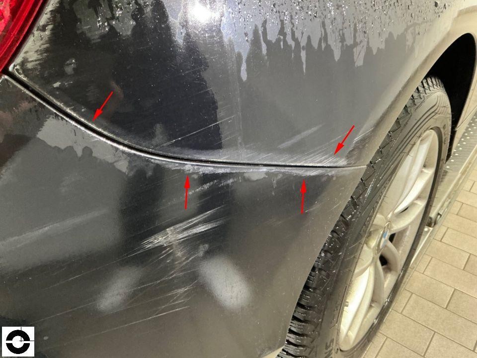 Hintere Stoßstange links mit deutlichen Kratzspuren und Schleifspuren, rote Pfeile markieren Schäden