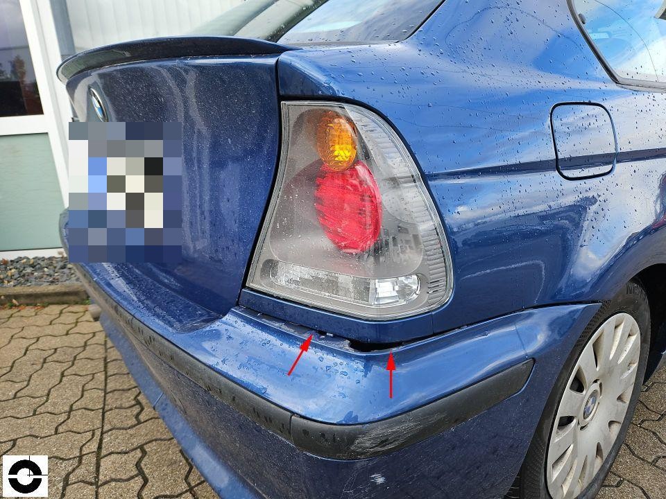 Heckansicht links, Stoßstange mit Kratzern und Beschädigungen, rote Pfeile markieren Schadenstellen