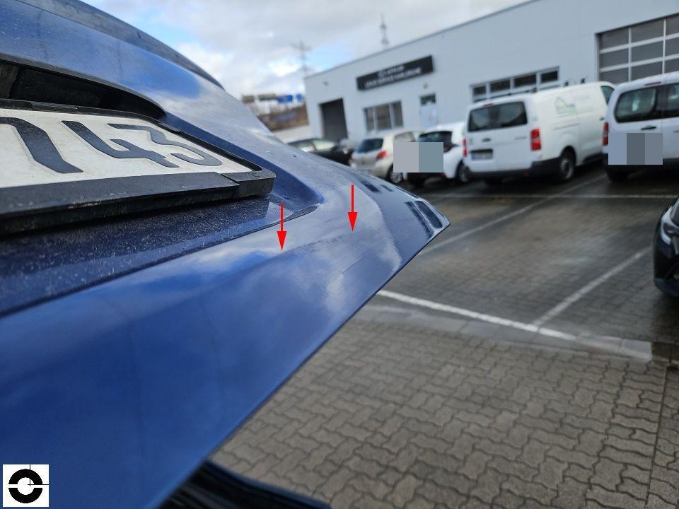 Heckklappe blau mit roten Pfeilen auf Kratzer/Lackschäden hinweisend, Parkplatz