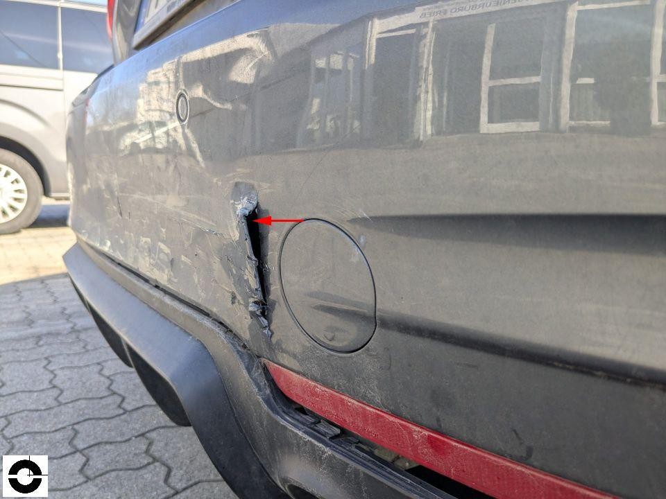 Heckschürze links mit tiefem Riss und Kratzer, roter Pfeil markiert Schadenstelle