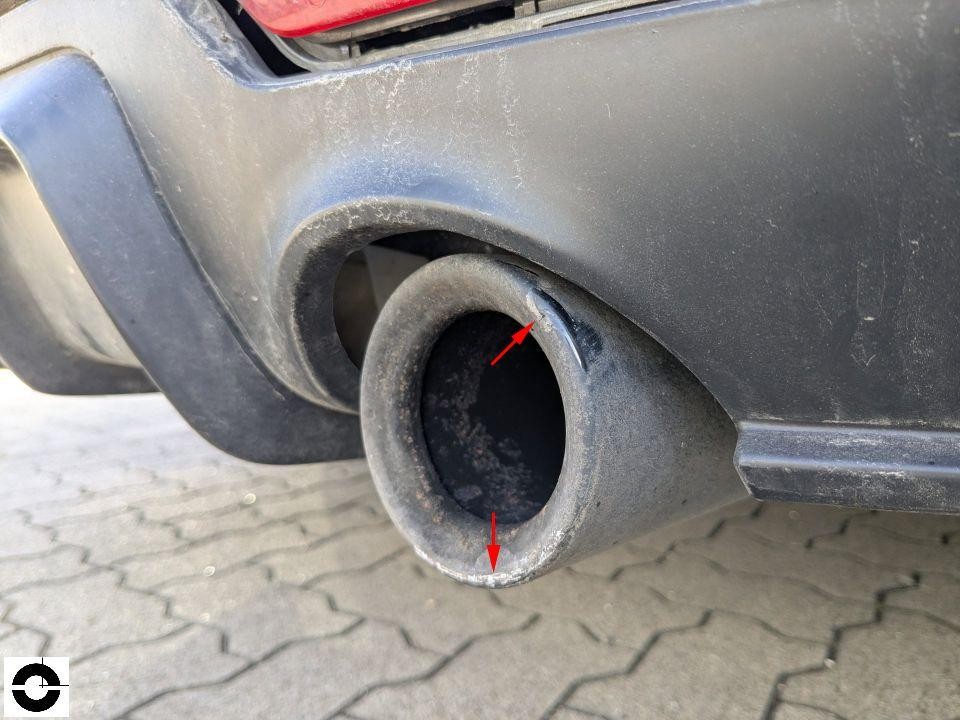 Heckschürze mit Auspuffblende, rote Pfeile markieren Kratzer und Beschädigungen