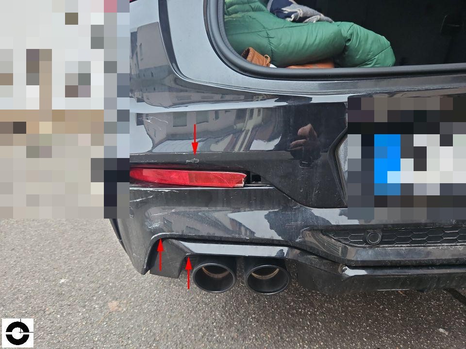 Heckansicht mit Schaden am hinteren Stoßfänger links, rote Markierungspfeile zeigen Kratzer und Beschädigungen, Kofferraum geöffnet