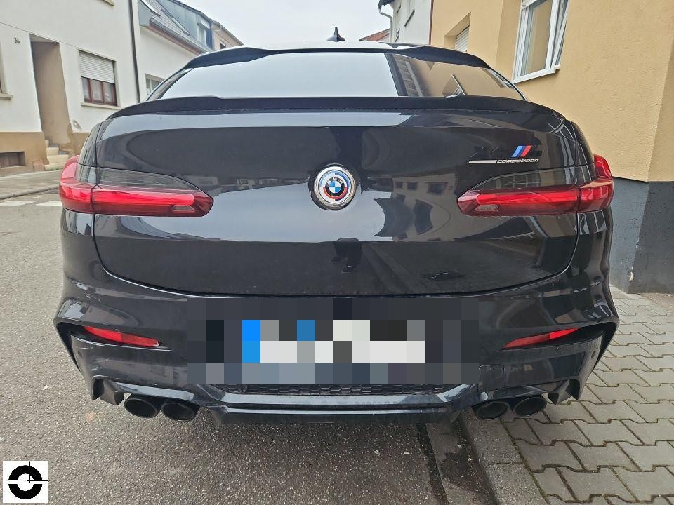 Heckansicht, schwarzes SUV mit M Competition Schriftzug, Kennzeichen pixeliert, keine sichtbaren Schäden