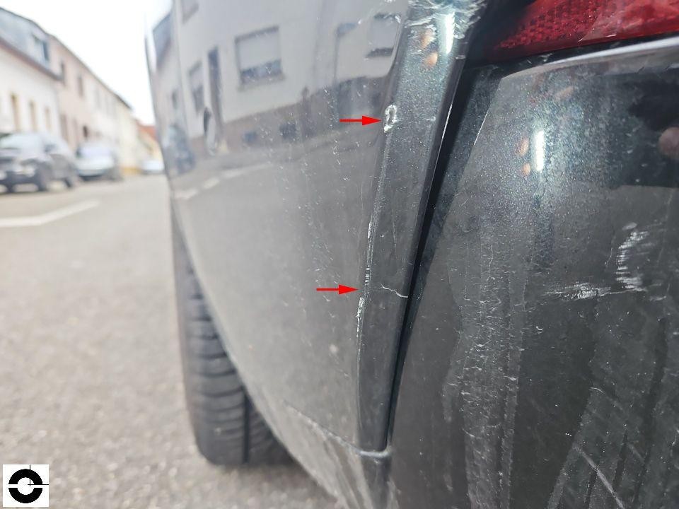 Hintere Stoßstange links mit Kratzern und Lackschäden, rote Pfeile markieren Schadstellen