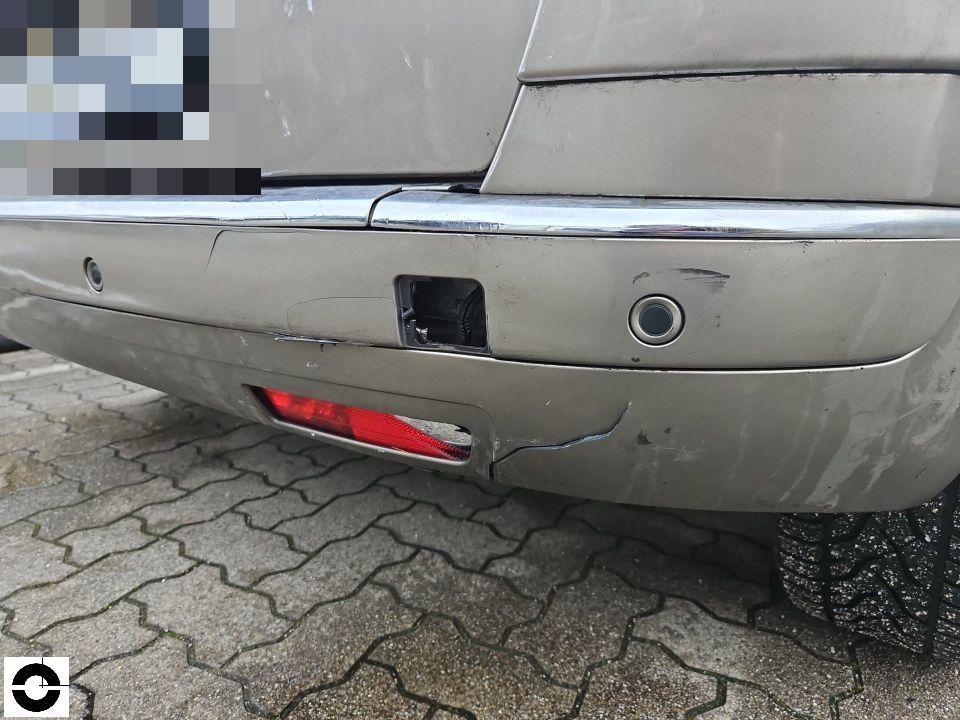 Heckansicht mit beschädigter Stoßstange, fehlende Abdeckung, Kratzer und Risse
