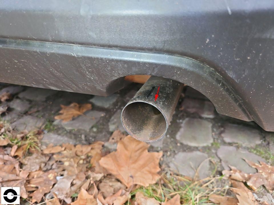 Auspuffendrohr hinten mit roter Markierung, Fahrzeug auf Kopfsteinpflaster