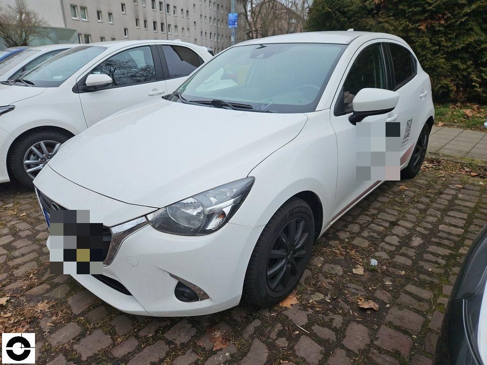 Frontansicht schräg links, weißer Kleinwagen auf Kopfsteinpflaster, keine sichtbaren Schäden