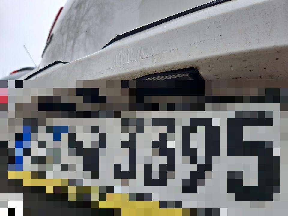 Frontbereich mit Schaden an Stoßstange, Kennzeichen pixeliert, Nahaufnahme von unten