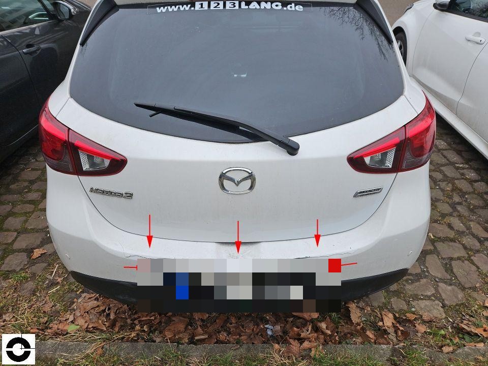 Heckansicht mit Markierungspfeilen auf Stoßstange und Heckklappe, Kratzer und Beschädigungen sichtbar