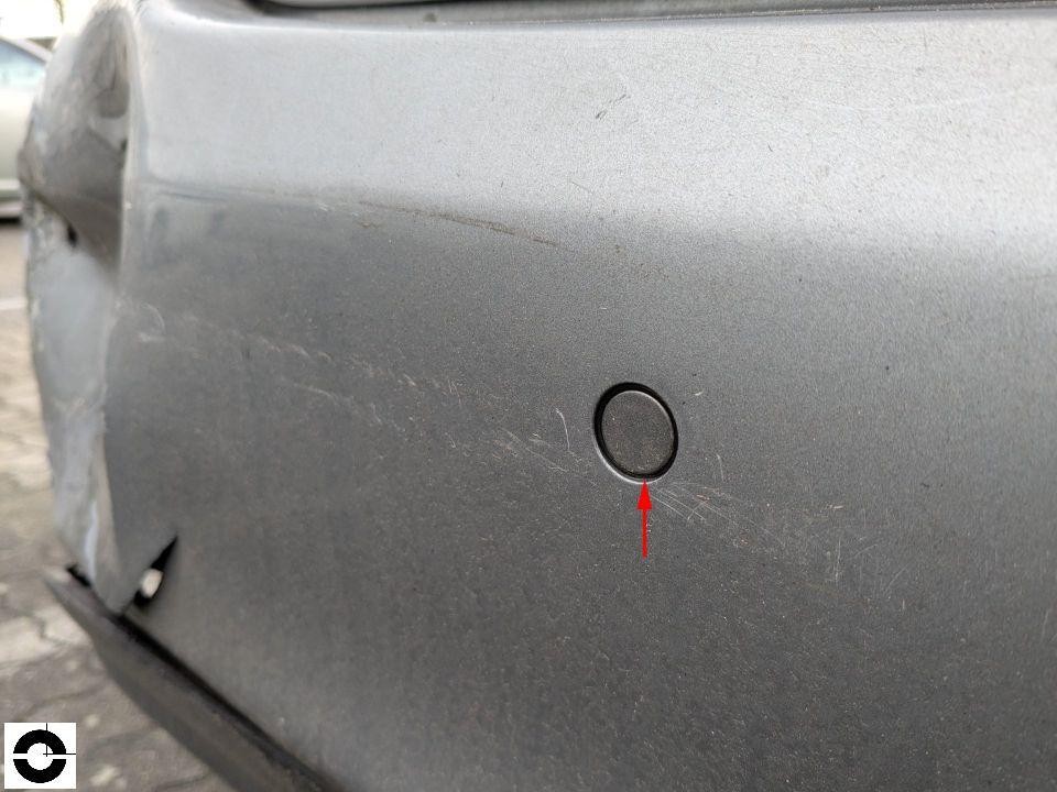 Hintere Stoßstange silbergrau mit Parksensor, Kratzer und rotem Markierungspfeil