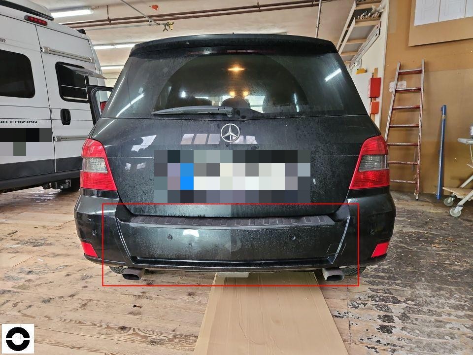 Heckansicht in Werkstatt, Stoßstange mit roter Markierung, stark verschmutzt