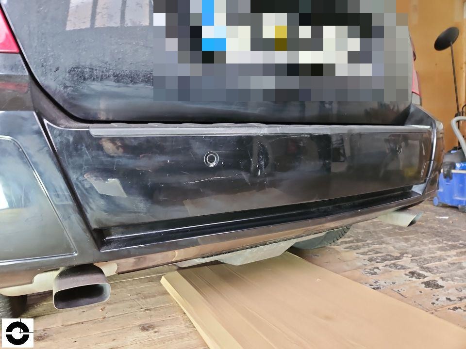 Heckansicht, schwarze Stoßstange mit Rückfahrkamera, Kennzeichenbereich pixeliert, leichte Kratzer sichtbar