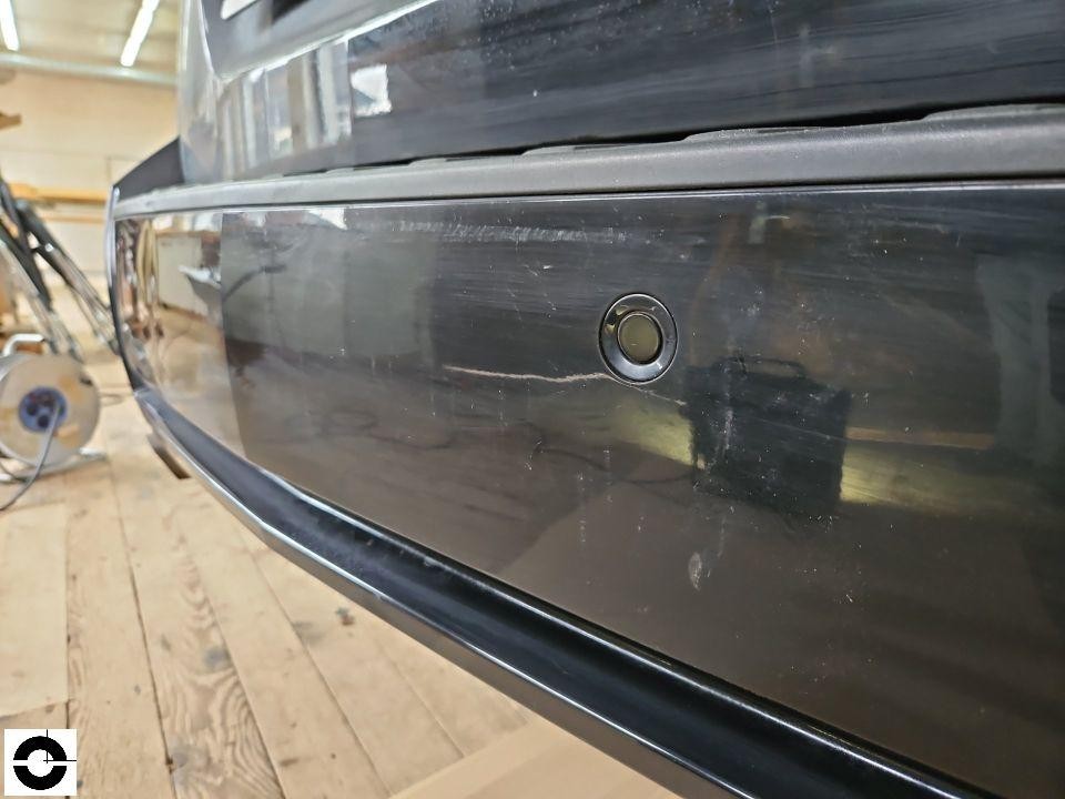 Heckschürze mit Einparksensor, Nahaufnahme, Kratzer auf schwarzem Lack sichtbar