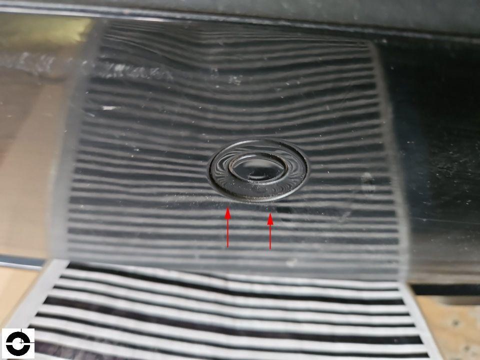 Kofferraumboden mit Gummimatte, rote Pfeile markieren Beschädigung nahe Ablauföffnung