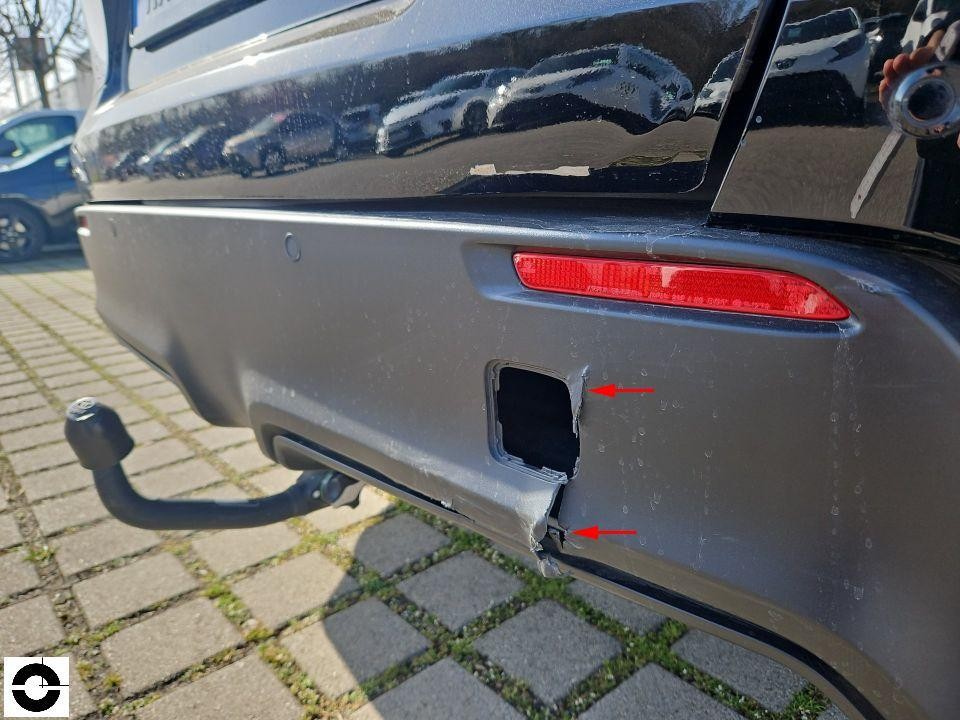 Heck-Stoßfänger links mit Beschädigung an PDC-Sensor-Abdeckung, rote Pfeile markieren Schaden