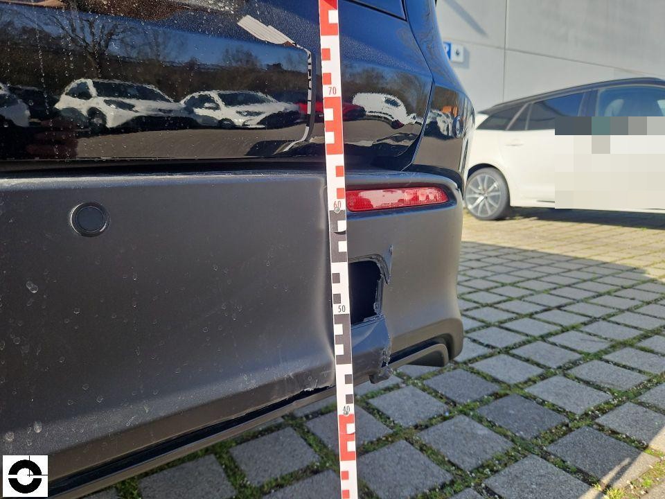 Heckansicht mit Messlatte, Schaden an rechter Stoßstangenecke und Abschleppösenabdeckung