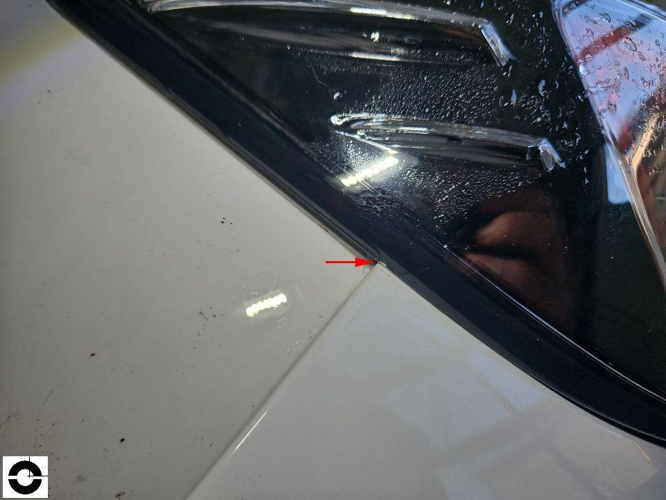 Detailaufnahme Übergang Motorhaube zur schwarzen Frontverkleidung, roter Pfeil markiert Spaltmaß/Beschädigung