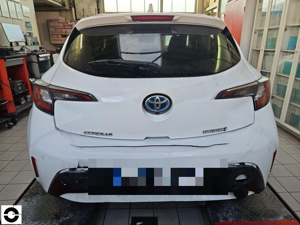 Heckansicht, deutlicher Schaden an Heckstoßstange mit Rissen und Verformung, Werkstattumgebung