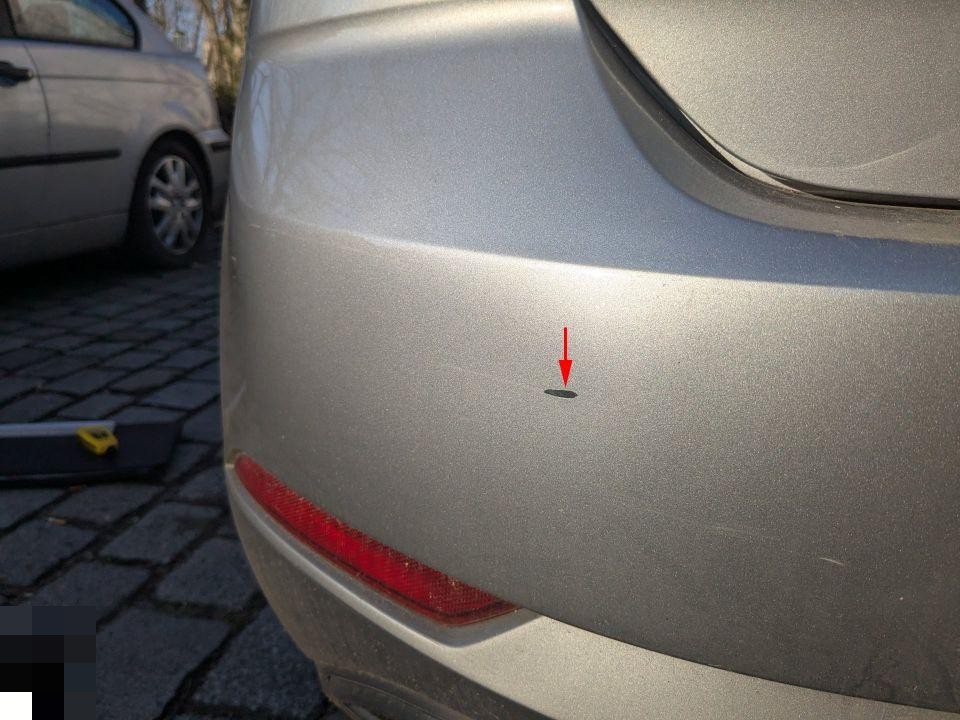 Heckschürze links mit rotem Pfeil auf Einparksensor, Reflektor sichtbar