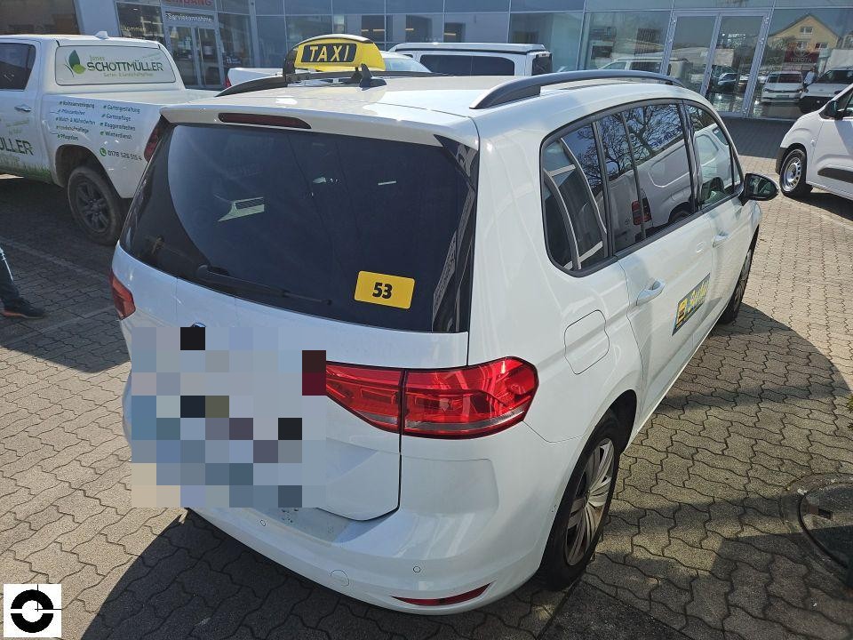 Heckansicht weißes Taxi mit gelbem Dachschild, Kennzeichen pixeliert, Parkplatz