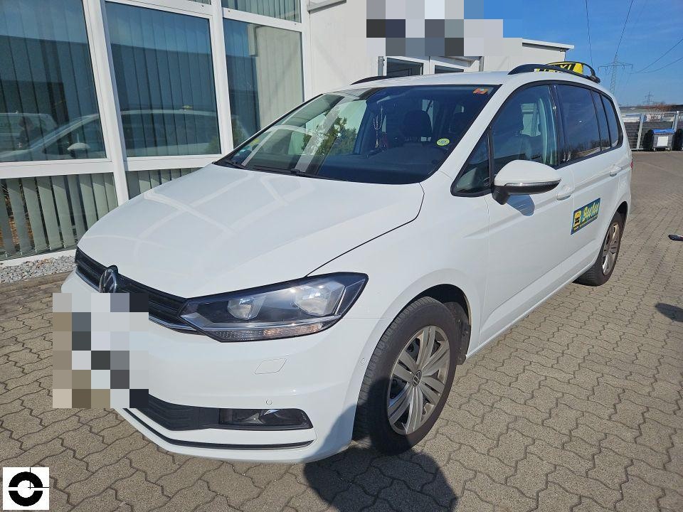 Taxi, Frontansicht schräg links, weißer Van mit Taxischild auf Dach, keine sichtbaren Schäden