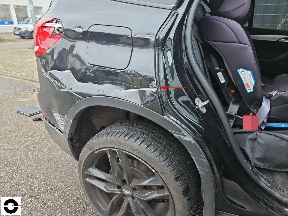 Heckansicht links mit massiver Delle und Verformung am hinteren Kotflügel, Tür geöffnet mit Kindersitz sichtbar