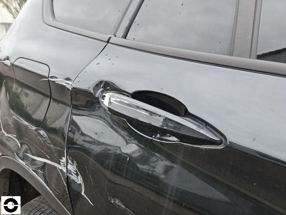 Hintere linke Tür mit Delle und Lackschaden am Türgriff, dunkelgraues Fahrzeug