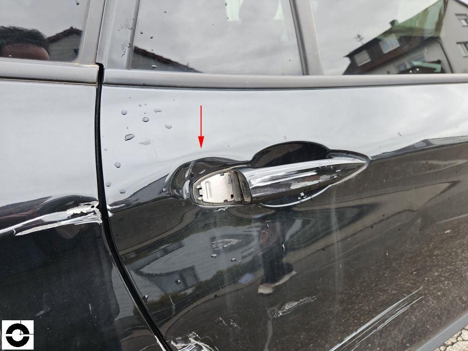 Hintere rechte Tür mit Hagelschäden, roter Pfeil markiert Delle bei Türgriff