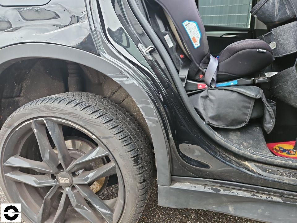 Linke Fahrzeugseite, geöffnete hintere Tür, massiver Schaden am hinteren Kotflügel und Radlauf, Kindersitz sichtbar