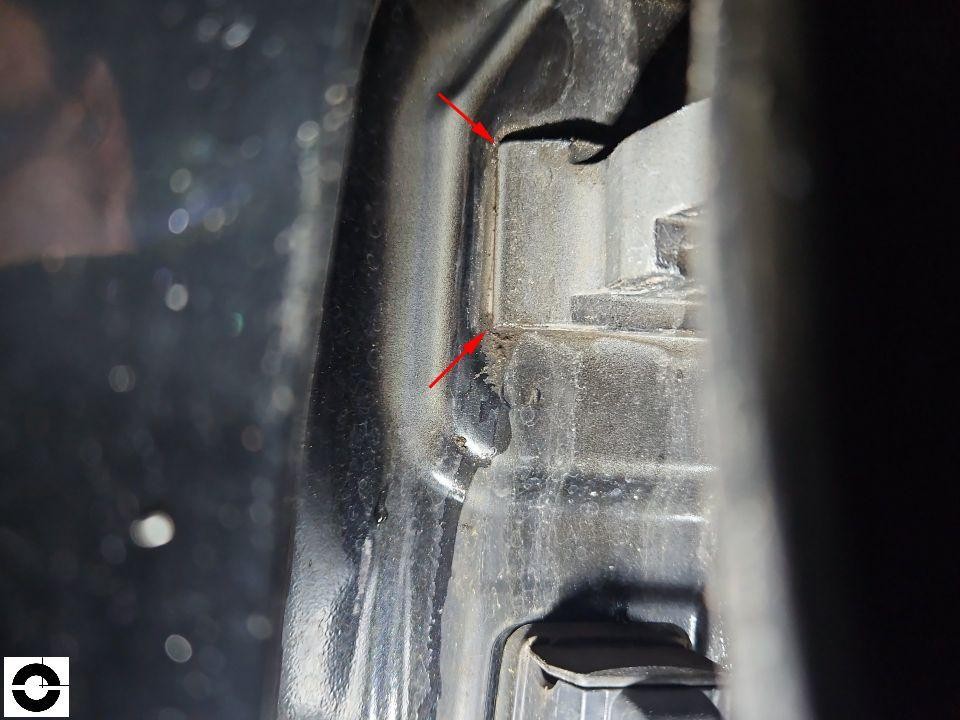 Detailaufnahme Karosserie-Innenseite mit roten Pfeilen auf Risse/Verformungen im Blech