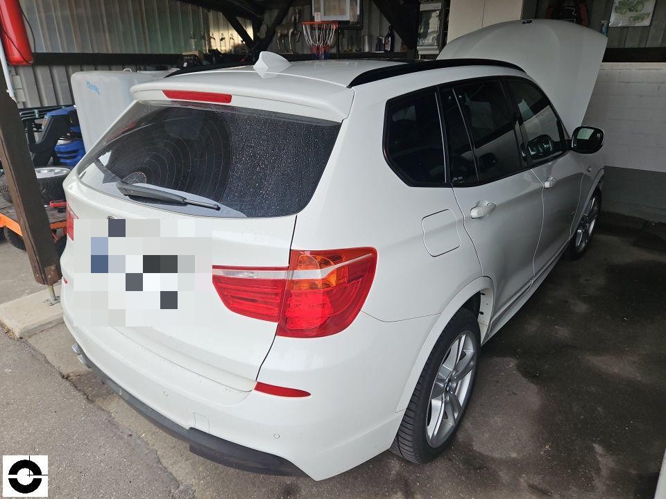 Heckansicht schräg rechts, Heckklappe geöffnet, weißes SUV in Werkstatt