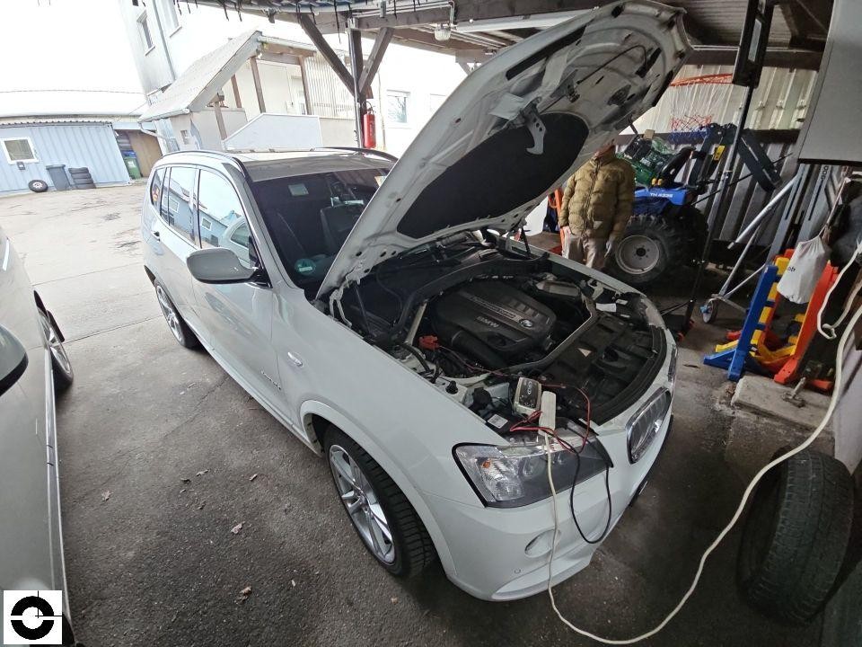 Motorraum mit geöffneter Haube, Diagnosegerät angeschlossen, Werkstattumgebung