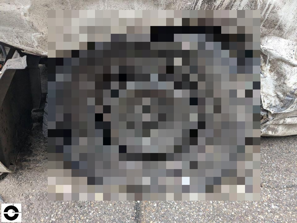 Demontiertes Fahrzeugteil auf Asphalt, daneben beschädigter Kotflügel