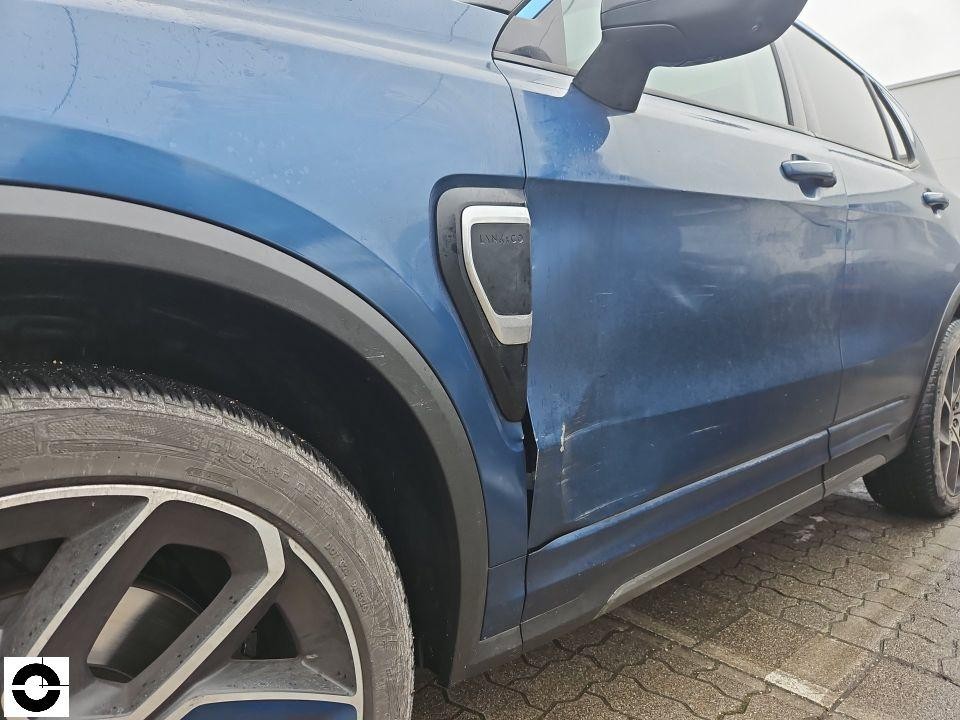 Linke Fahrzeugseite, Schaden am vorderen Kotflügel und Fahrertür, Kratzer und Dellen sichtbar