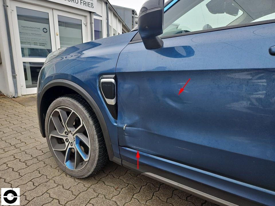 Linke Fahrzeugseite, vorderer Kotflügel und Tür mit Kratzern und Dellen, rote Pfeile markieren Schäden