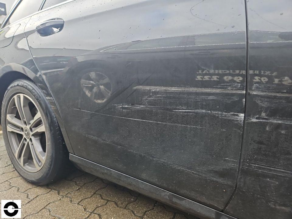Linke Fahrzeugseite mit deutlichen Schleif- und Kratzspuren an hinterer Tür