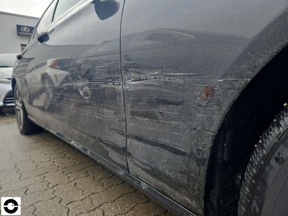 Linke Fahrzeugseite mit starken Kratzern und Schleifspuren an hinterer Tür und Kotflügel