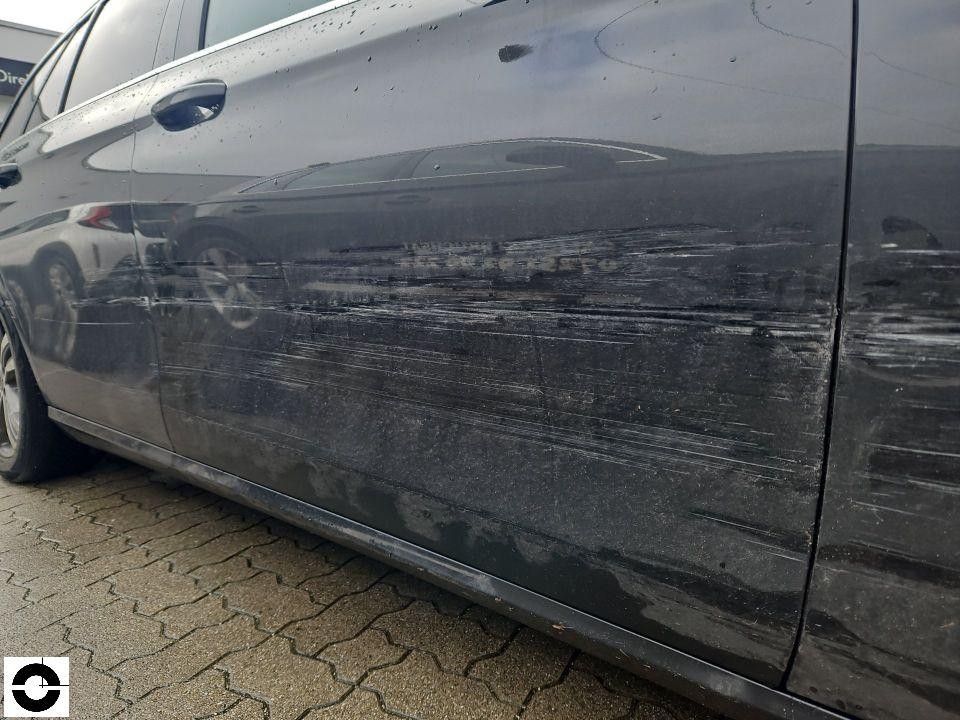 Seitenansicht linke Fahrzeugseite mit langen horizontalen Kratzspuren an Tür und Schweller